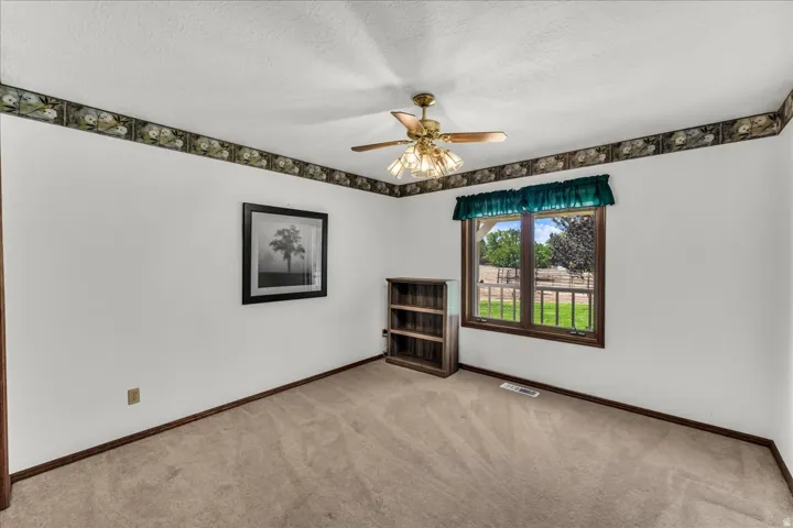 Carpeted flooring, ceiling fan, and a window with exterior views