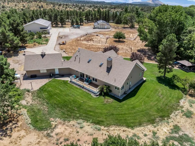Expansive property featuring a main residence with a large deck, detached garage, and a large additional structure