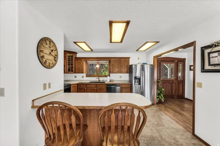 Kitchen featuring wood cabinetry, stainless steel refrigerator, tile flooring, and a breakfast bar with a solid surface countertop