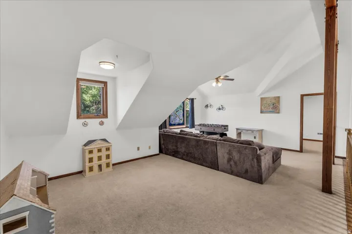 Sloped ceilings with exposed wood-finish structural beam, recessed window, and wall-mounted light fixture