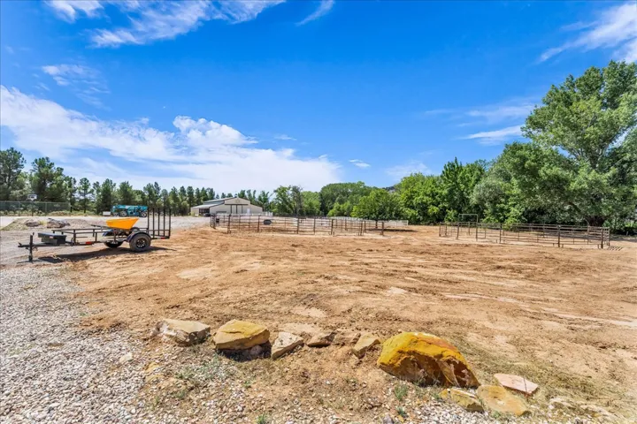 Expansive cleared area with perimeter fencing, a large outbuilding, and mature trees