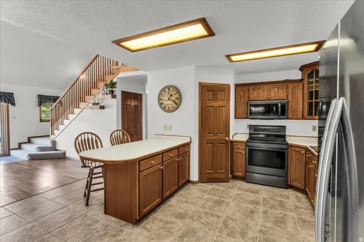 Kitchen featuring wood-finish cabinetry, integrated appliances, and a central island with countertop seating