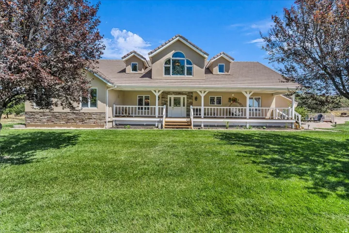 Stucco exterior with stone accents, covered front porch, dormer windows, and arched transom window