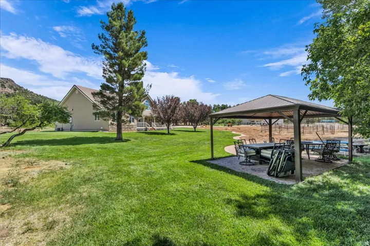 Expansive green lawn with a metal-roofed gazebo, featuring a paved base and a walking path
