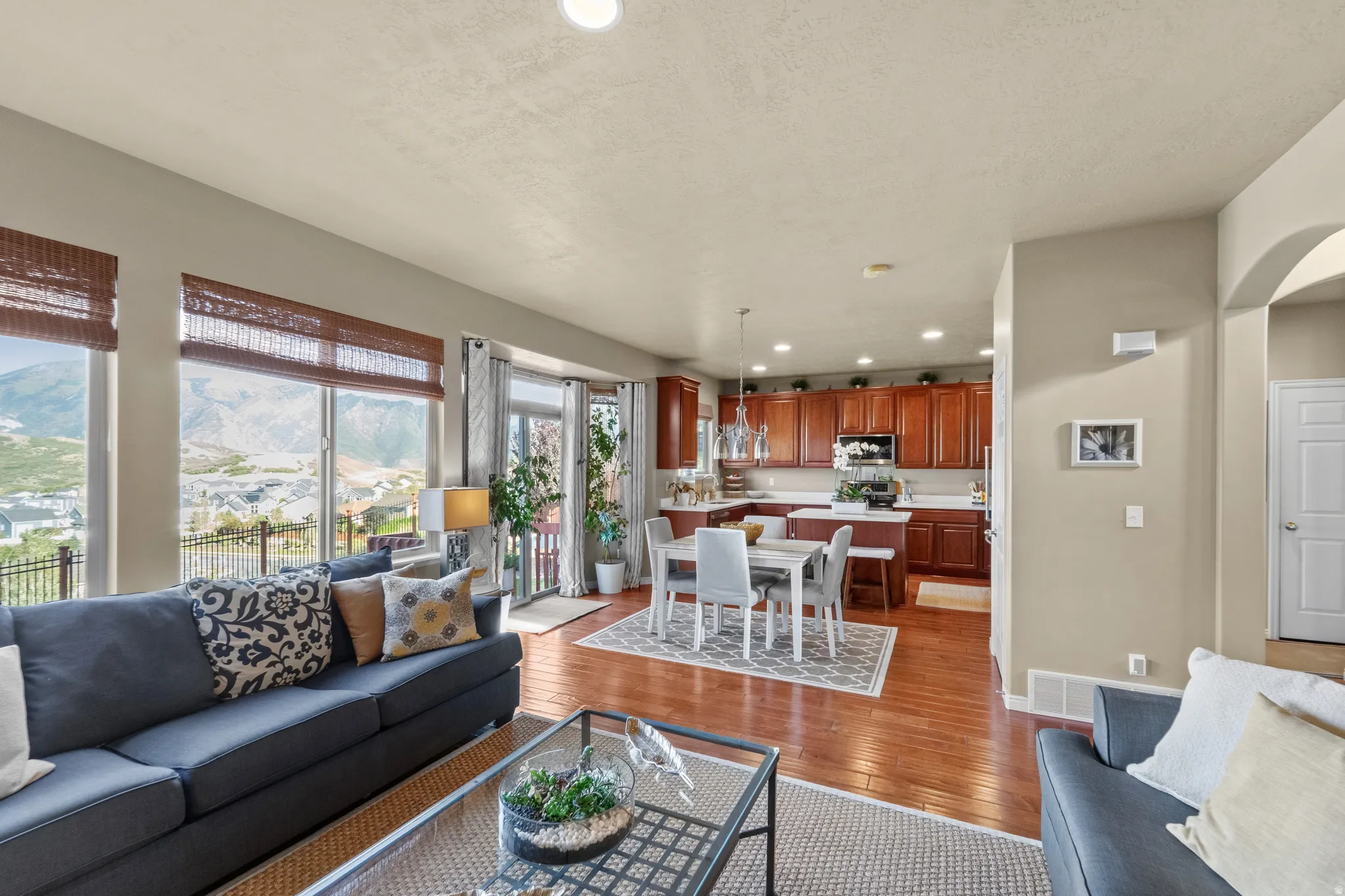 Open-concept living area with wood-finish flooring, a kitchen featuring wood cabinetry and white countertops, and a dining area