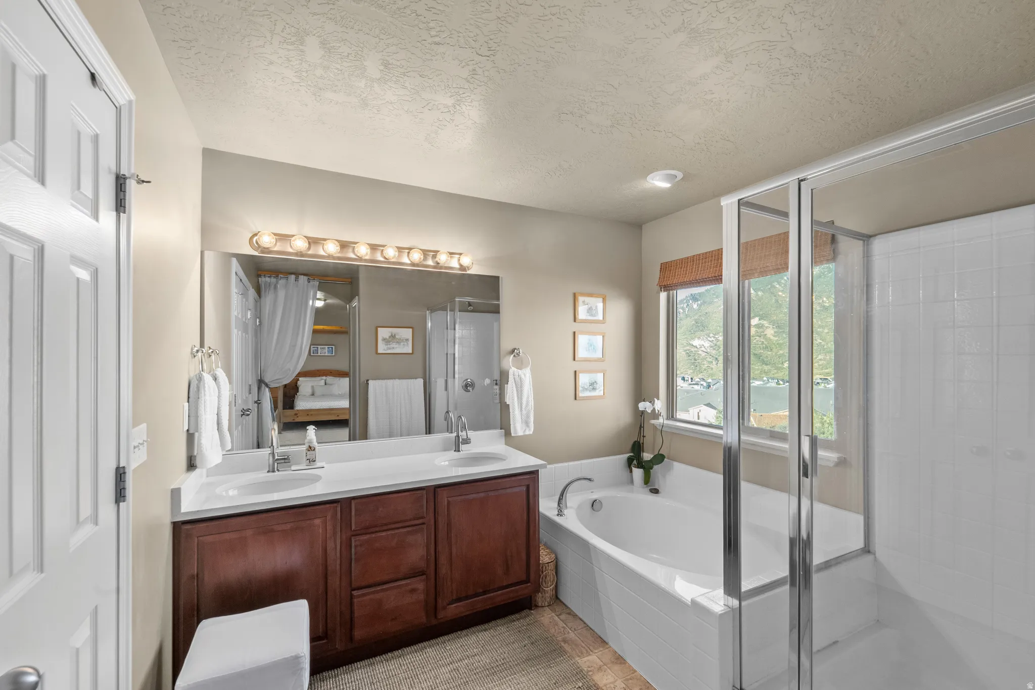 Master Suite Bathroom Dual vanity with white countertops, integrated bathtub, separate glass-enclosed shower, and a large window