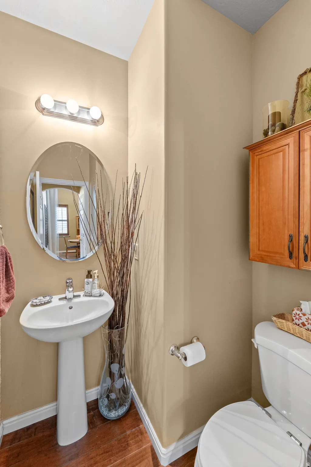 Half Bath perfect for guests on the Main Level Pedestal sink with chrome faucet, oval wall mirror, and vanity light fixture