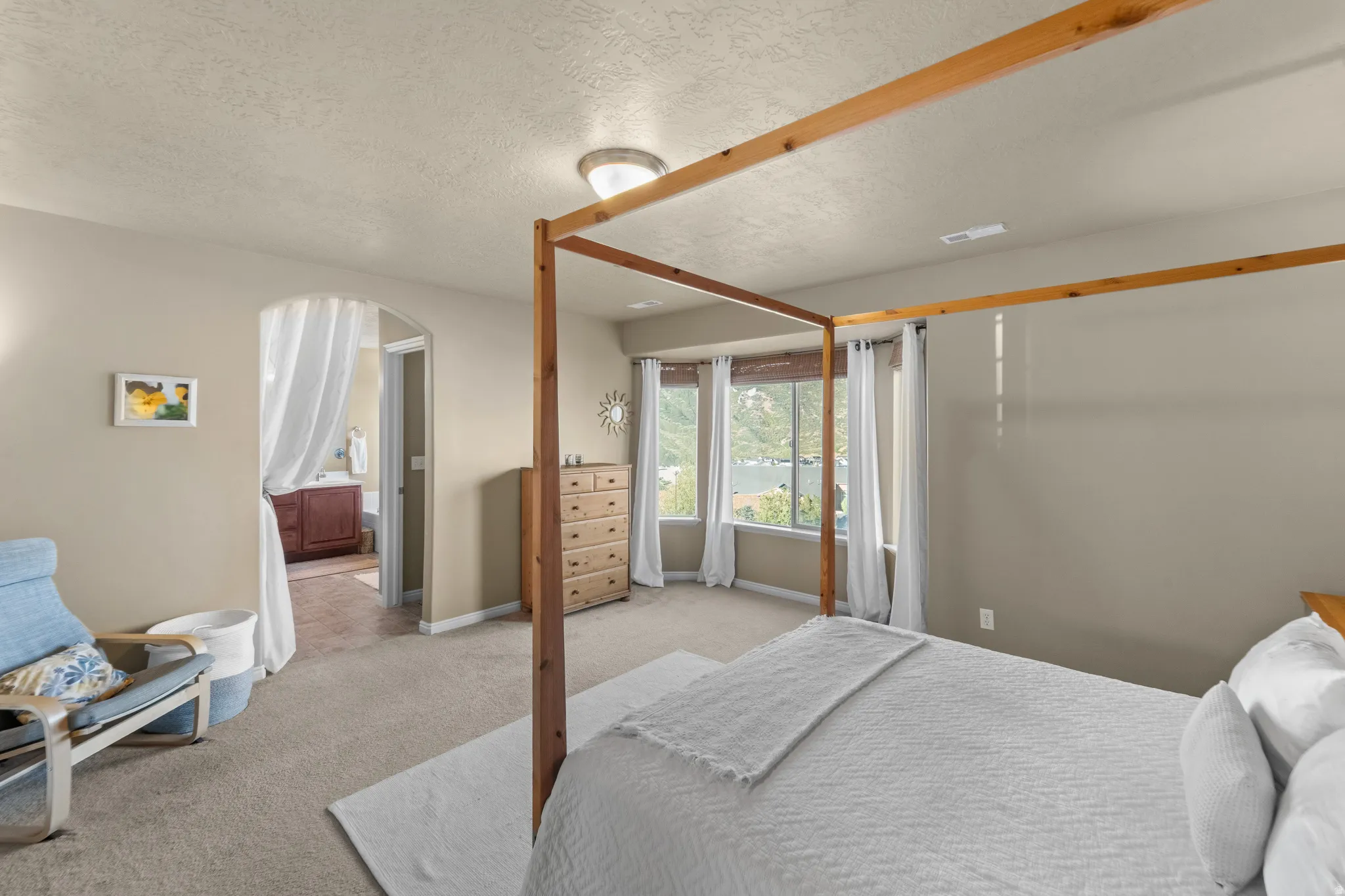 Master Suite Carpeted flooring throughout, arched doorway leading to a separate area, and built-in vanity with cabinetry