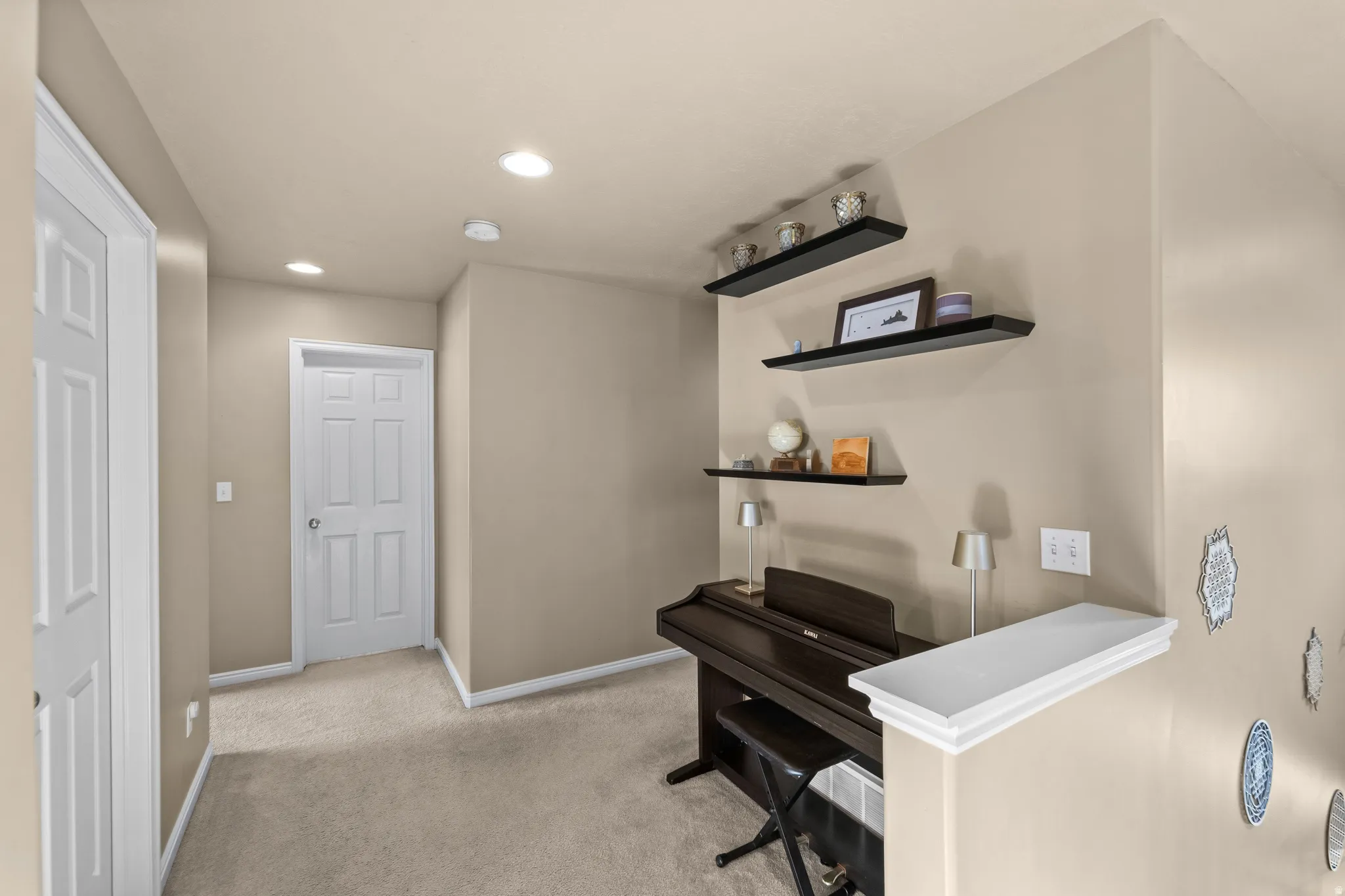 Open area as you come upstairs to the main bedrooms. Recessed ceiling lighting illuminates the hallway, featuring warm neutral wall tones and light-colored carpeting