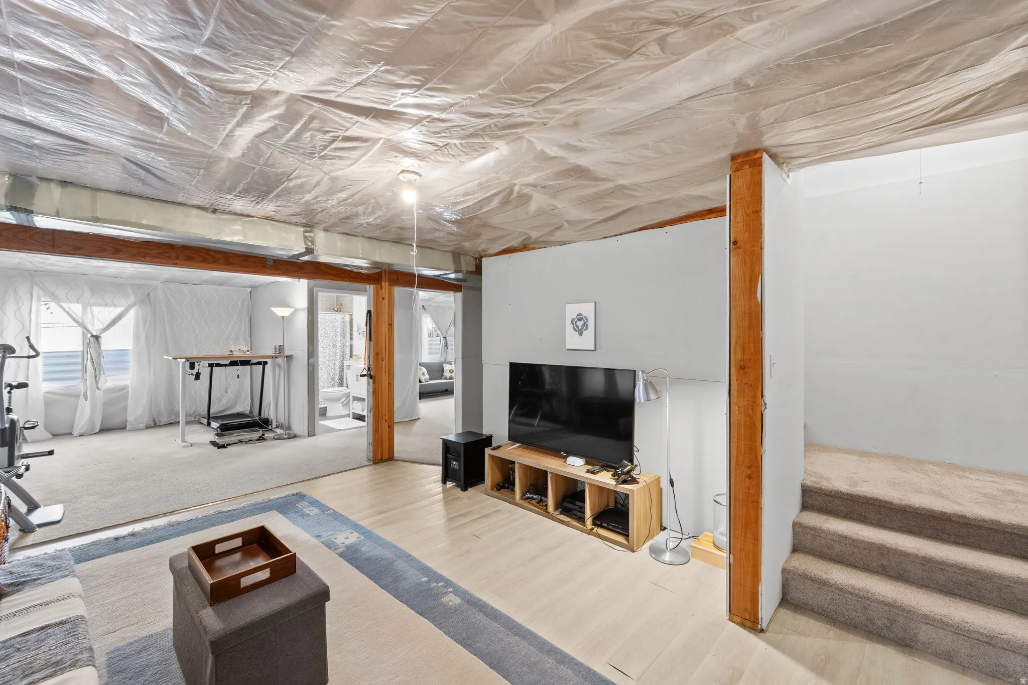 Finished wood beams, light wood-finish flooring, and carpeted stairs