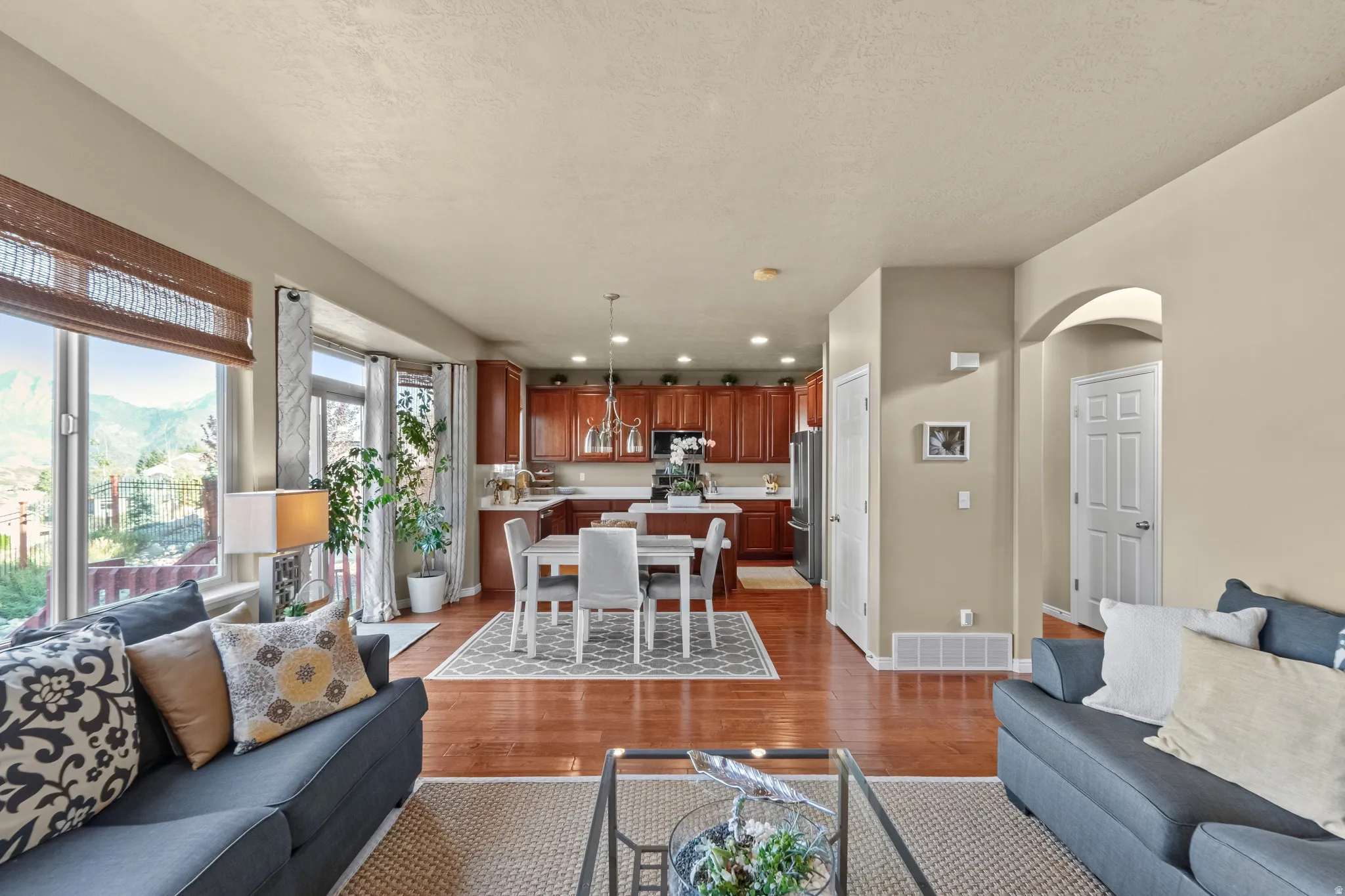 Hardwood-style flooring throughout, kitchen with cherry wood finish cabinetry, recessed lighting, and a white countertop island