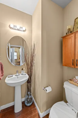 Half Bath perfect for guests on the Main Level Pedestal sink with chrome faucet, oval wall mirror, and vanity light fixture