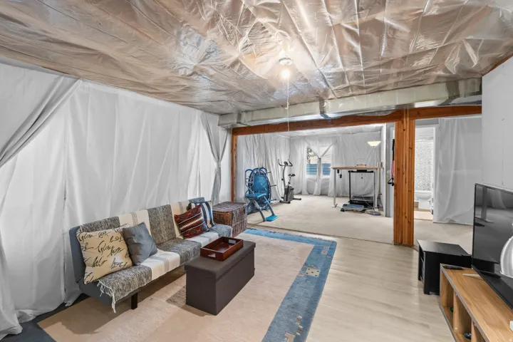 Basement almost finished Open lower-level space with wood-finish flooring, exposed wooden beams, and recessed lighting