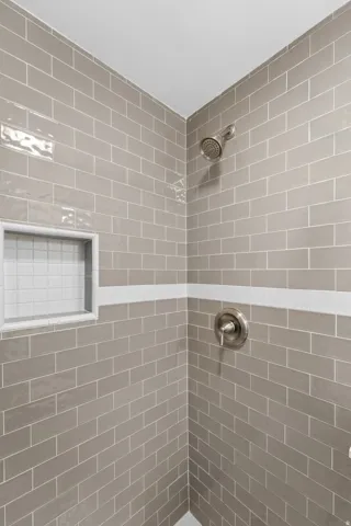 Finished basement Shower featuring gray subway tile, a recessed niche with white square tile, and brushed nickel fixtures