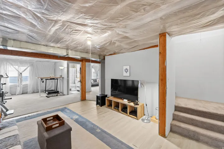 Finished wood beams, light wood-finish flooring, and carpeted stairs