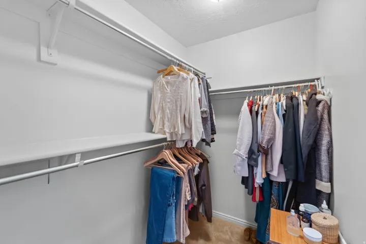 Master Suite Walk in Closet . Right half of the walk in closet in Master Suite. Walk-in closet with carpet flooring, white walls, and built-in shelving