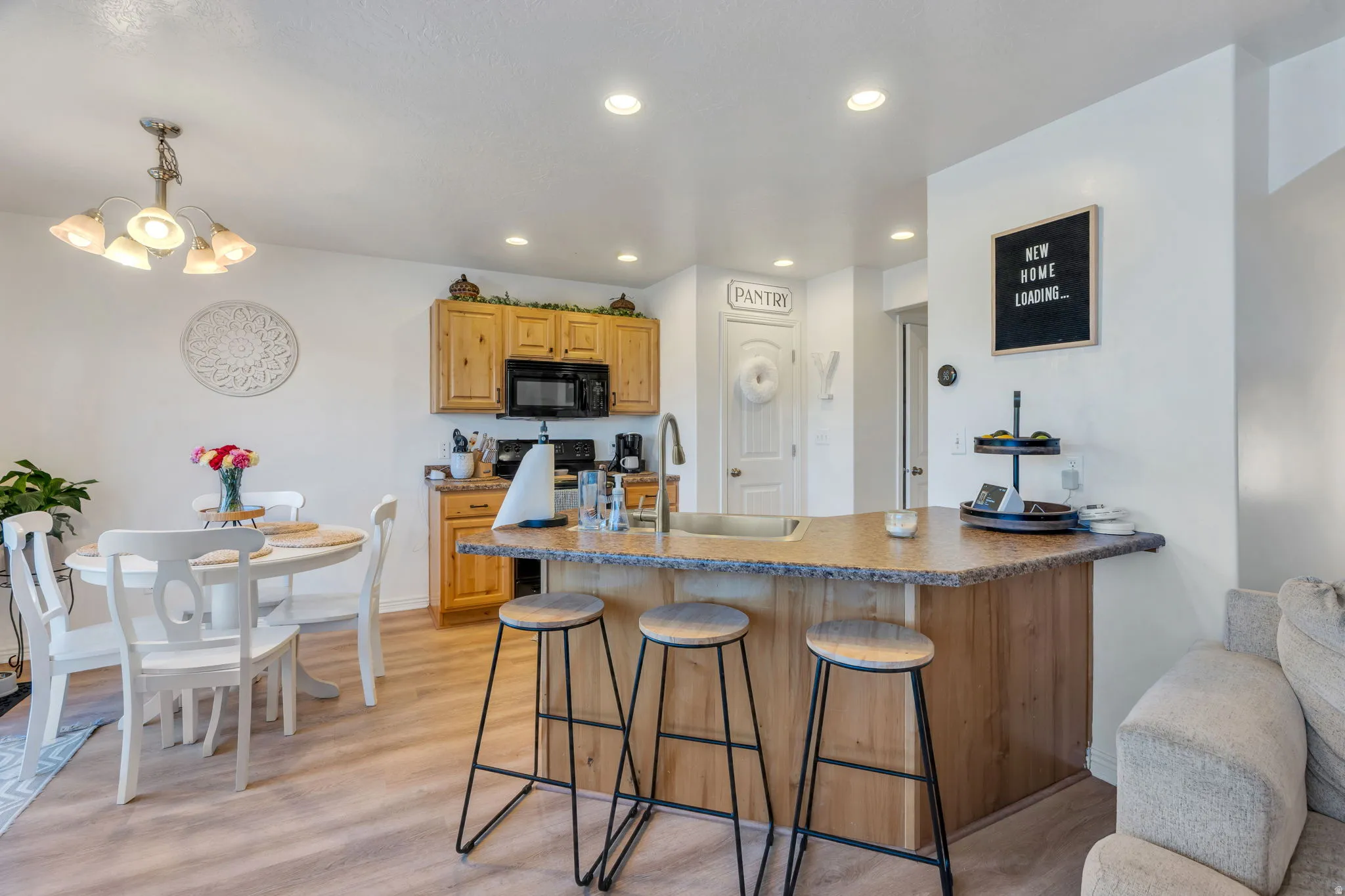 Kitchen featuring wood cabinetry, black appliances, a breakfast bar, and recessed lighting