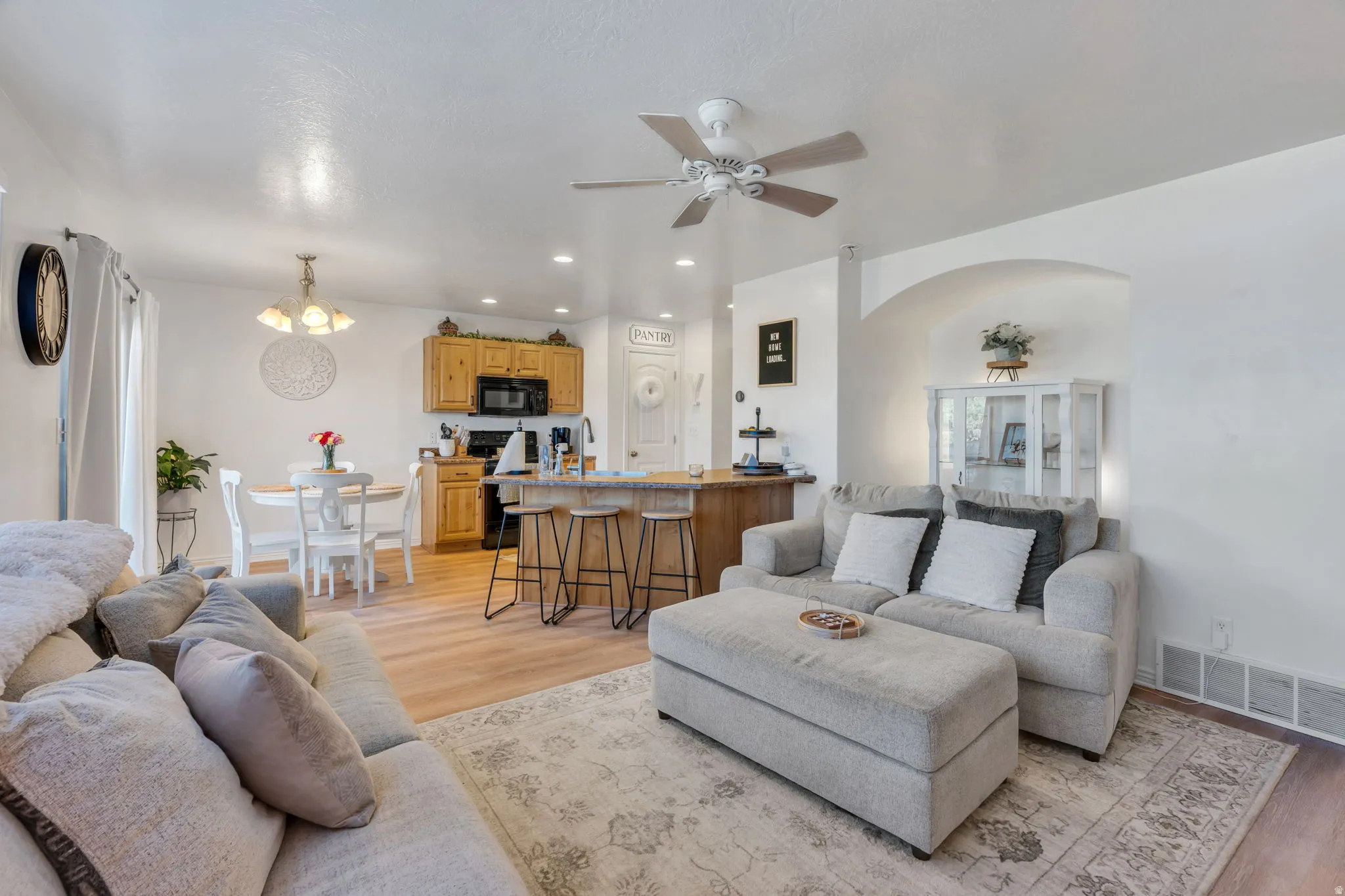 Wood-finish flooring throughout, light wood cabinetry, recessed lighting, ceiling fan, and a built-in arched alcove