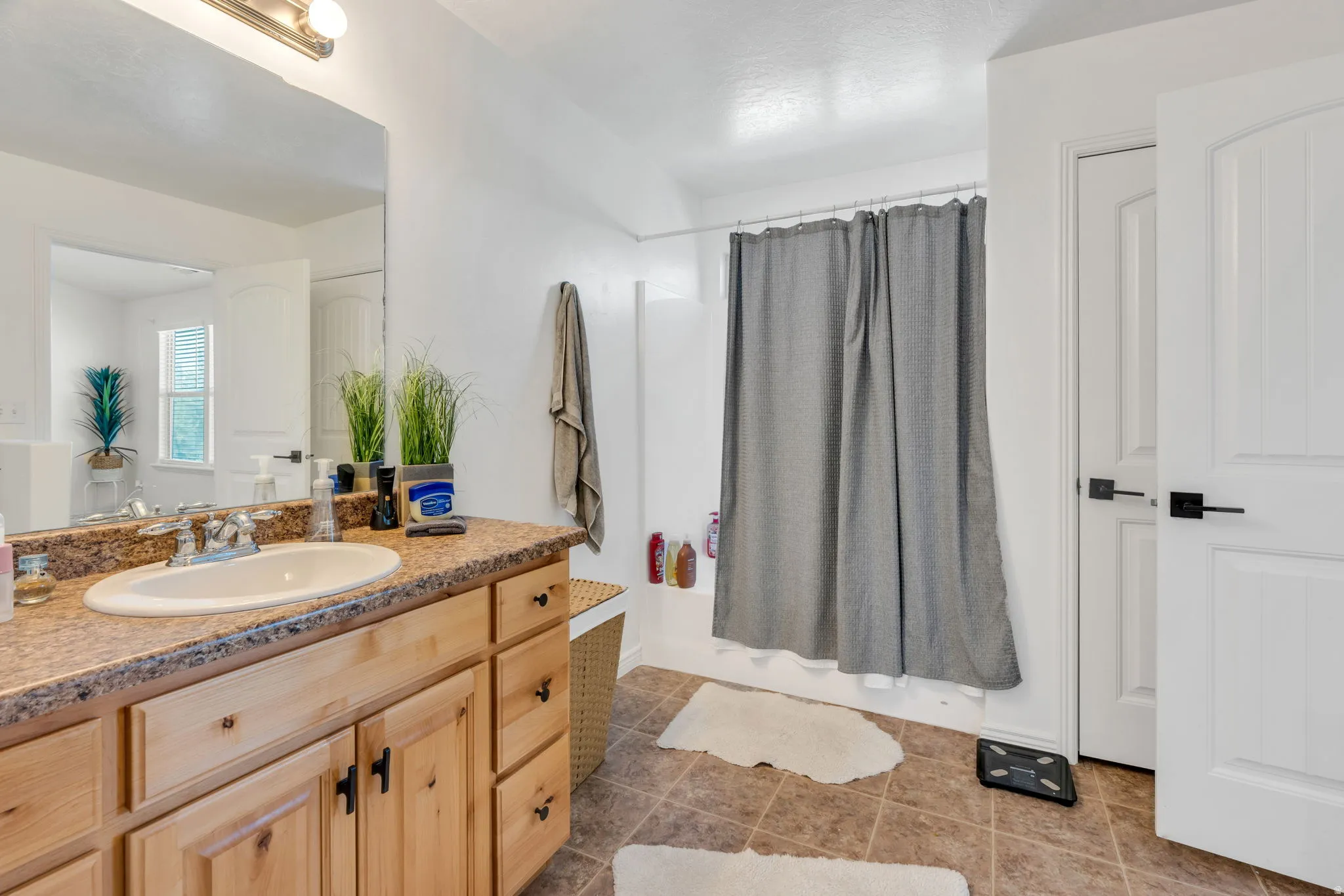 Vanity with wood-finish cabinetry, integrated sink, and a speckled countertop