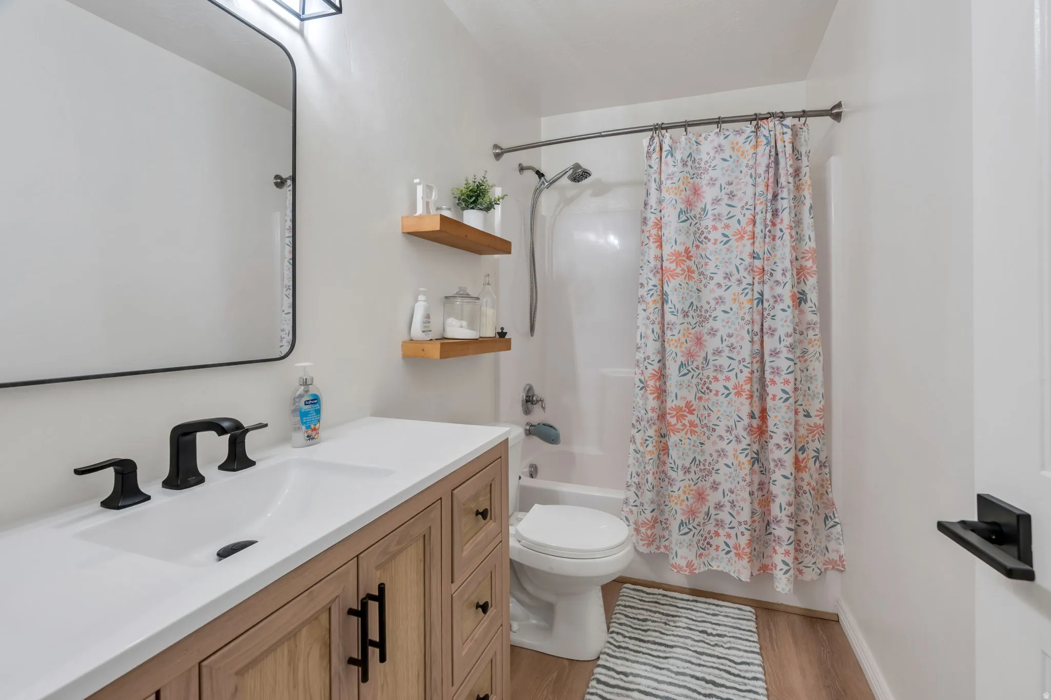 White vanity countertop with an integrated sink, matte black faucet, and wood-finish cabinetry