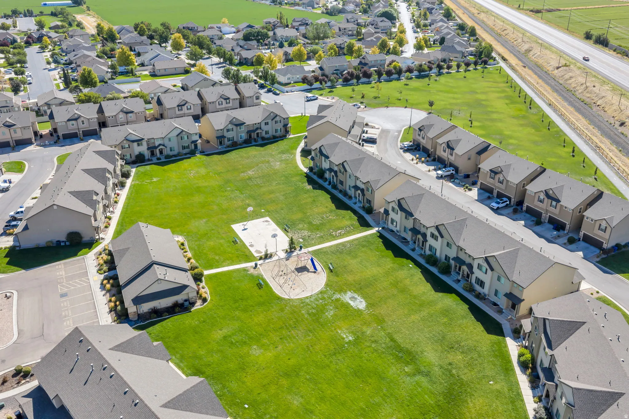 Community green space with a playground, surrounded by multi-story residential buildings featuring gabled roofs and individual parking areas