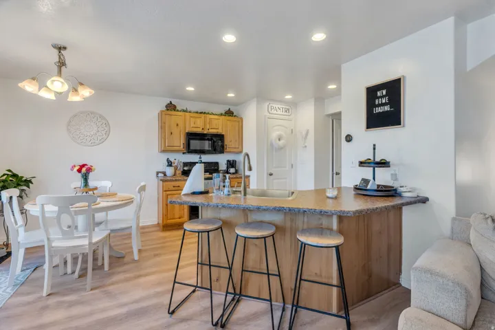 Kitchen featuring wood cabinetry, black appliances, a breakfast bar, and recessed lighting