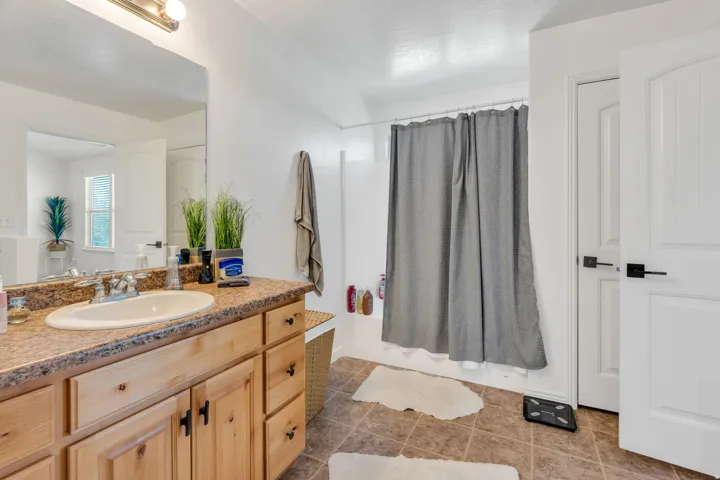 Vanity with wood-finish cabinetry, integrated sink, and a speckled countertop