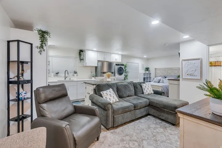 Integrated living space featuring a full kitchen with white cabinetry and stainless steel appliances