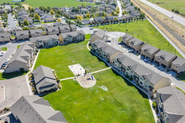 Community green space with a playground, surrounded by multi-story residential buildings featuring gabled roofs and individual parking areas