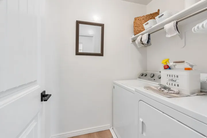 Dedicated laundry area featuring white walls, open shelving, a metal hanging rod, and light wood-finish flooring