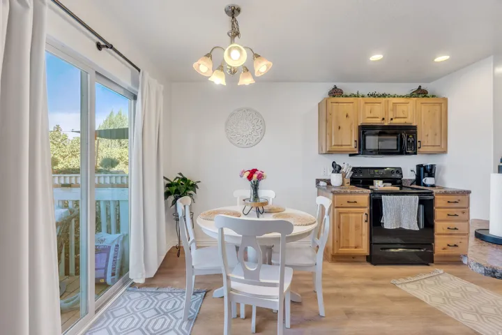 Wood-finish flooring, wood cabinetry, black appliances, built-in microwave, and sliding glass door