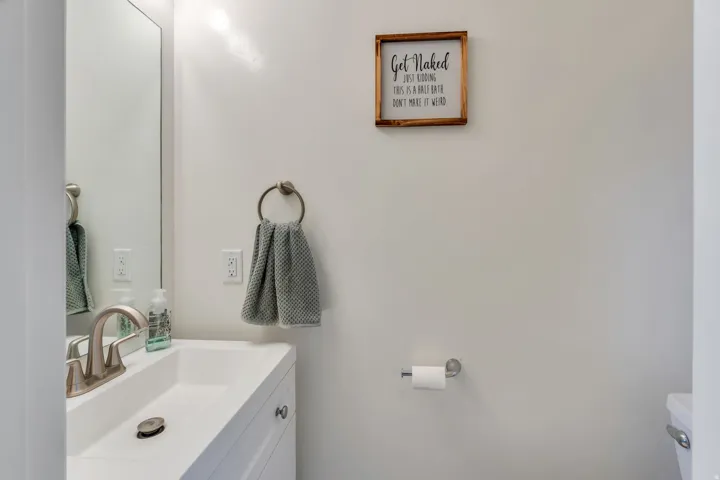 White vanity with brushed nickel hardware, integrated sink, brushed nickel faucet, and wall-mounted mirror