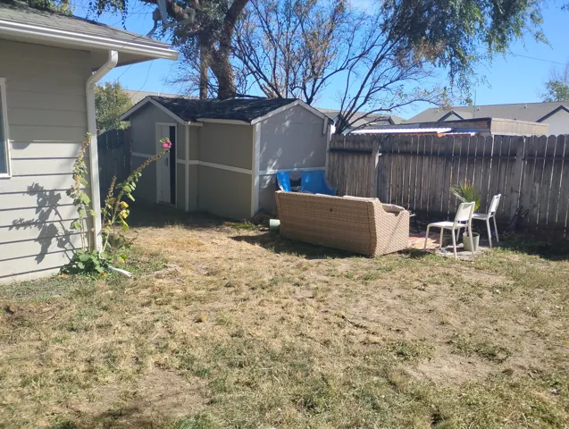 Fenced backyard with wood privacy fencing, a storage shed, and a small patio area