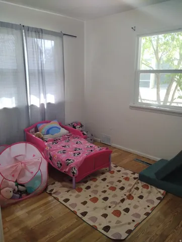 Hardwood-style flooring with white baseboards, bright white walls, and a large window providing natural illumination