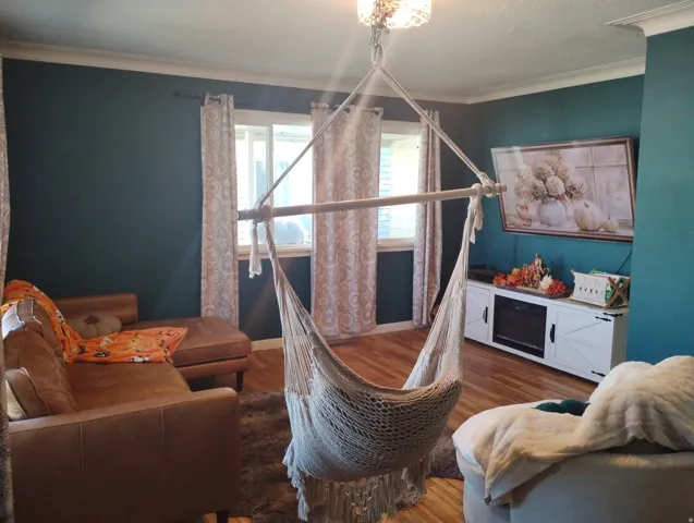 Hardwood flooring, crown molding, double windows, white built-in media console, and an integrated electric fireplace