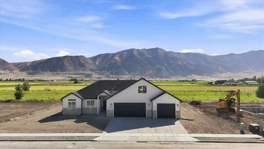 Modern farmhouse exterior featuring board and batten siding, stone accents, dark trim, and a two-car garage