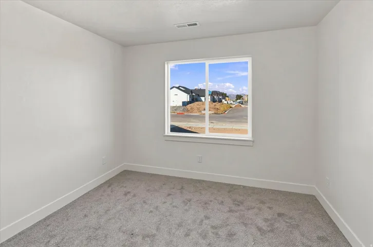 White walls, carpeted flooring, and a large window with white trim