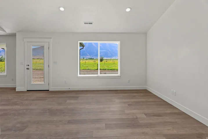 Spacious room featuring wood-finish flooring, recessed lighting, and a glass-paneled exterior door