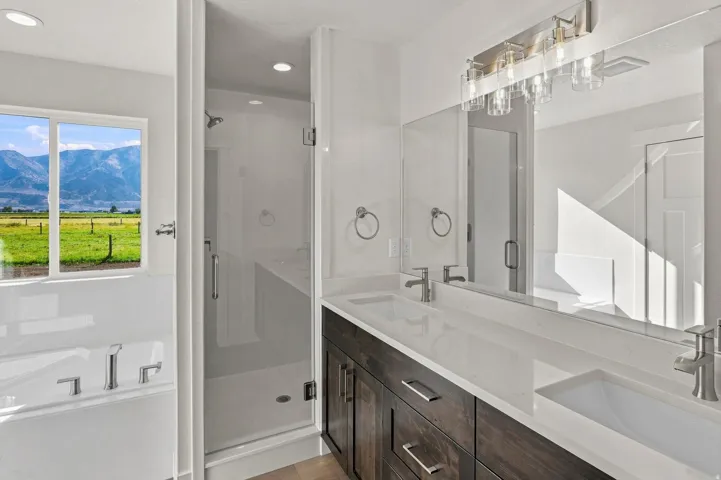 Double vanity with rectangular undermount sinks, brushed nickel fixtures, and a glass-enclosed shower with a built-in bench