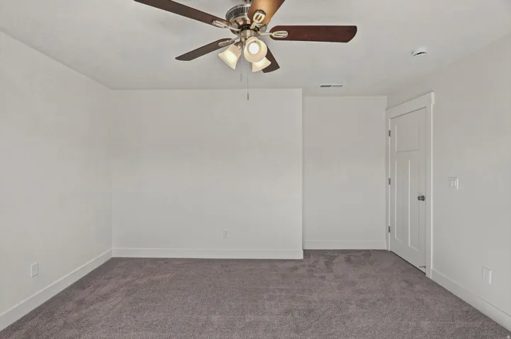 Neutral wall color, ceiling fan with integrated lighting, textured carpet, and a three-panel interior door
