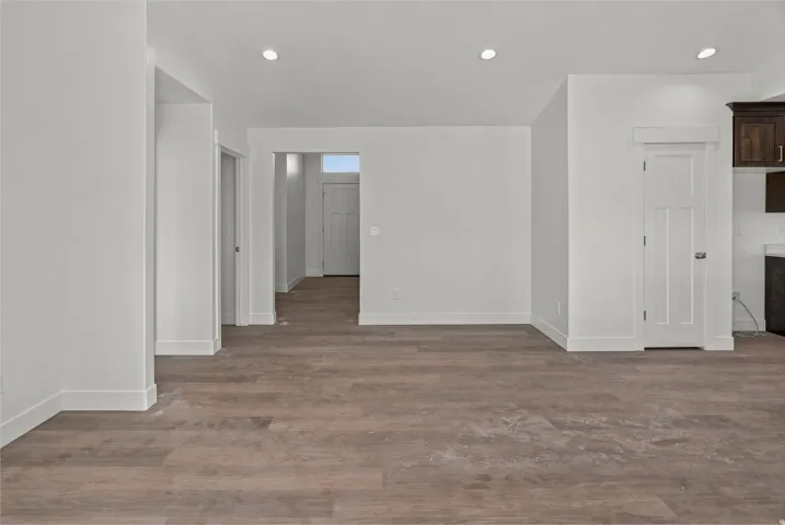Wood-finish flooring throughout, recessed ceiling lighting, white interior walls, and contemporary interior doors