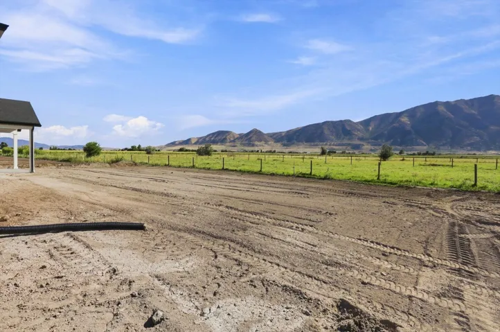 Expansive parcel with mountain backdrop, surrounded by agricultural land and a perimeter fence