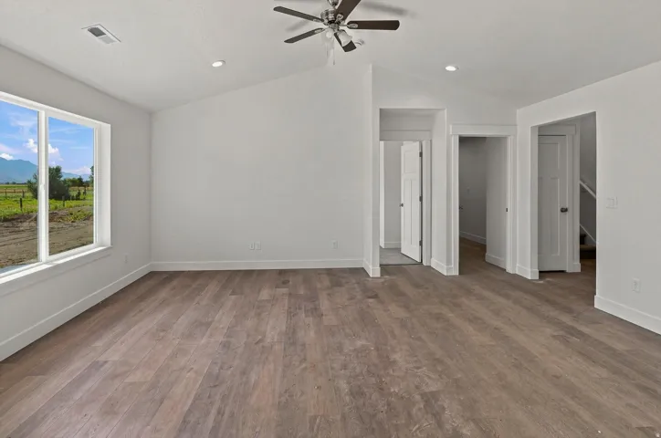 Vaulted ceiling with recessed lighting, wood-finish flooring, ceiling fan, and white trim throughout