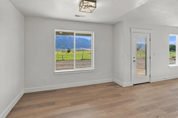 Wood-finish flooring, white walls, and a contemporary flush-mount ceiling light