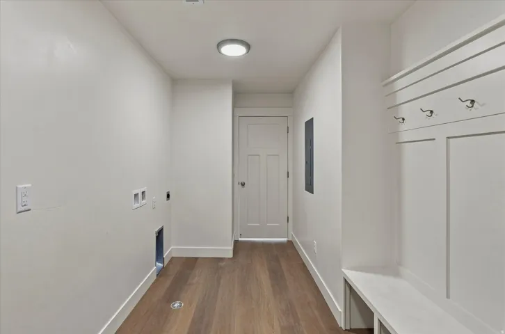 Mudroom featuring wood-finish flooring, built-in bench, wall-mounted coat hooks, and recessed lighting