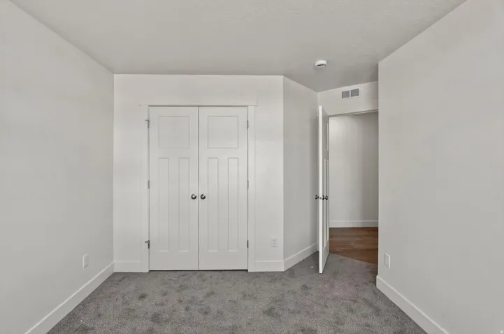 Recessed double-door closet, soft gray carpeting, white painted walls, and white trim