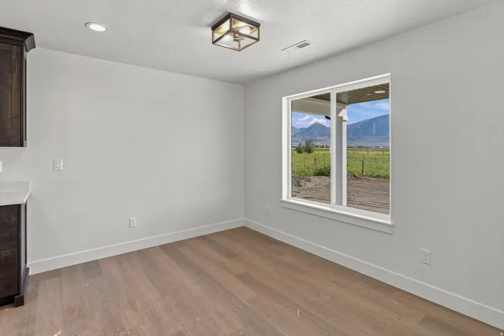 Wood-finish flooring, recessed lighting, and a modern ceiling fixture complement the neutral wall finishes