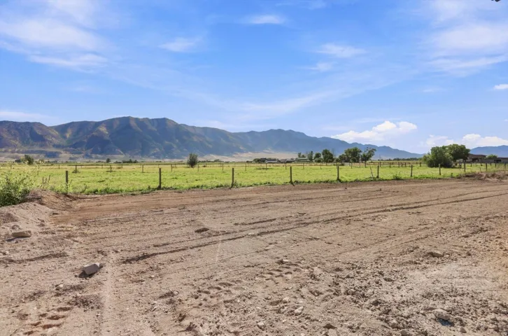 Expansive open land with a dirt road, partial fencing, and distant mountain backdrop