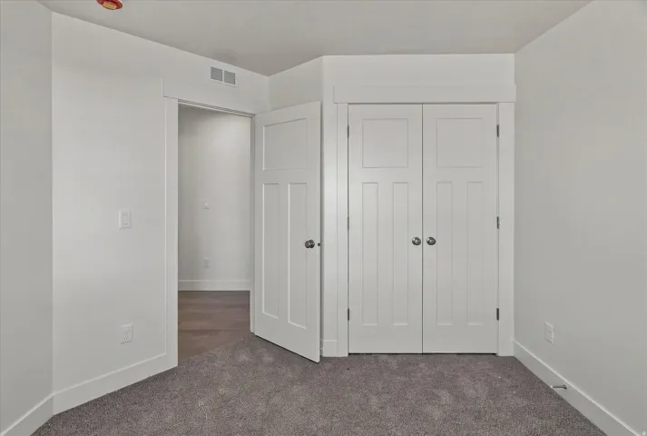 White shaker-style closet doors with brushed nickel hardware, gray carpet, and white trim