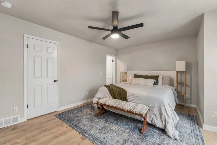 Wood-finish flooring with a neutral wall color, white trim, and a black ceiling fan